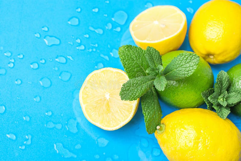 Ripe Organic Citrus Fruits Lemon Limes Whole and Halved with Fresh Mint on Light Blue Background with Water Drops. Morning Sunligh