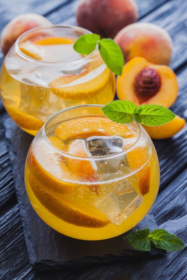 Ripe Peaches Cocktail with Ice and Fresh Mint on a Blue Table Stock
