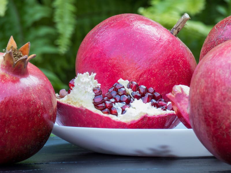 Ripe pomegranates  on dark wooden table and green background