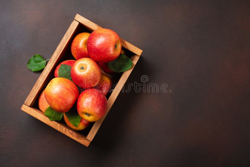 Ripe red apples in wooden box on a rusty background