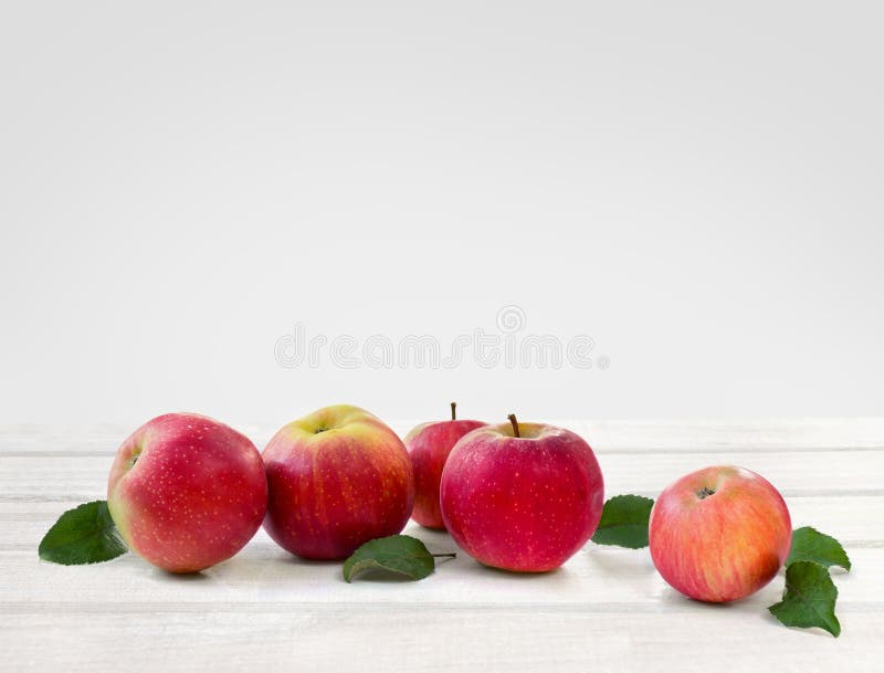 Ripe red juicy apples and leaves apple tree on white wooden table on a light background with space for text