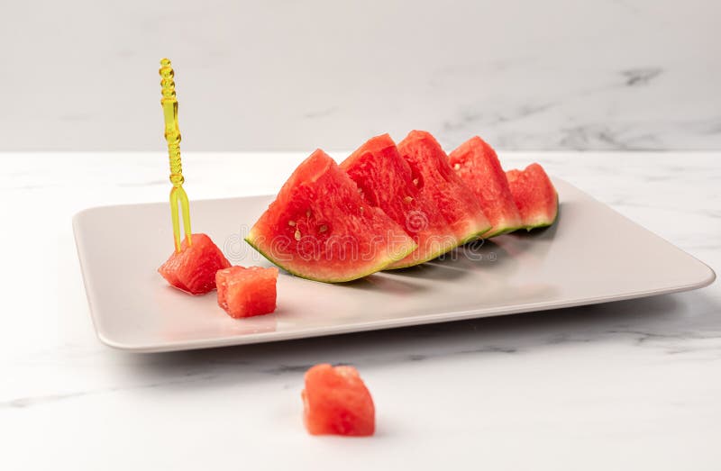 A ripe watermelon is cut into triangular segments lying on a plate. Disposable food plug. Triangular cut watermelon stock images, royalty-free photos and pictures
