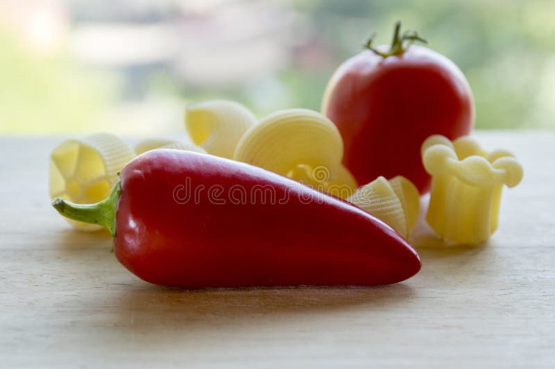 Ripened red jalapeno, red tomato and various mix of pasta on wooden table, ready for cooking royalty free stock images Ripened red jalapeno, red tomato and various mix of pasta on wooden table, ready for cooking royalty free stock images