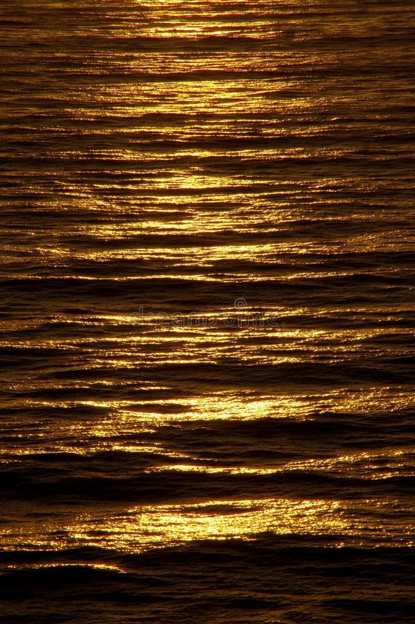 L'ultima luce del giorno si trasforma la superficie increspata del mare un ramato, di colore dorato.