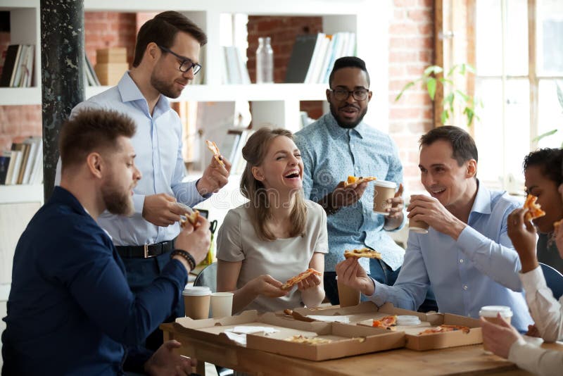 Happy diverse team people talking laughing at funny joke eating ordered pizza in office, friendly employees group enjoy positive emotions sharing lunch together having fun at work break on friday. Happy diverse team people talking laughing at funny joke eating ordered pizza in office, friendly employees group enjoy positive emotions sharing lunch together having fun at work break on friday