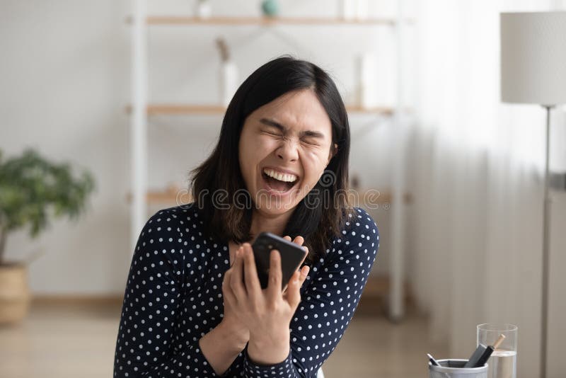Risas millennial asiática mujer viendo linda comedia en línea por teléfono imagen de archivo libre de regalías