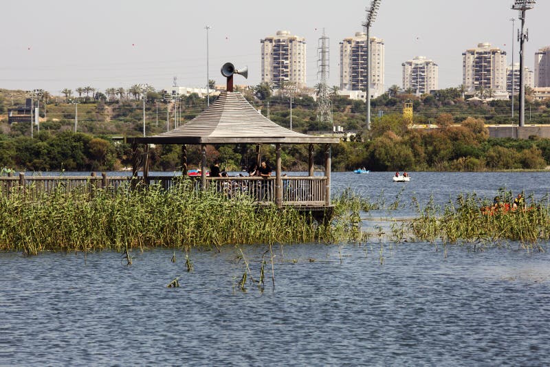 RISHON LE ZION, ISRAEL -APRIL 14, 2018: People walk along a wooden walking bridge near the lake in Rishon Lezion, Israel.