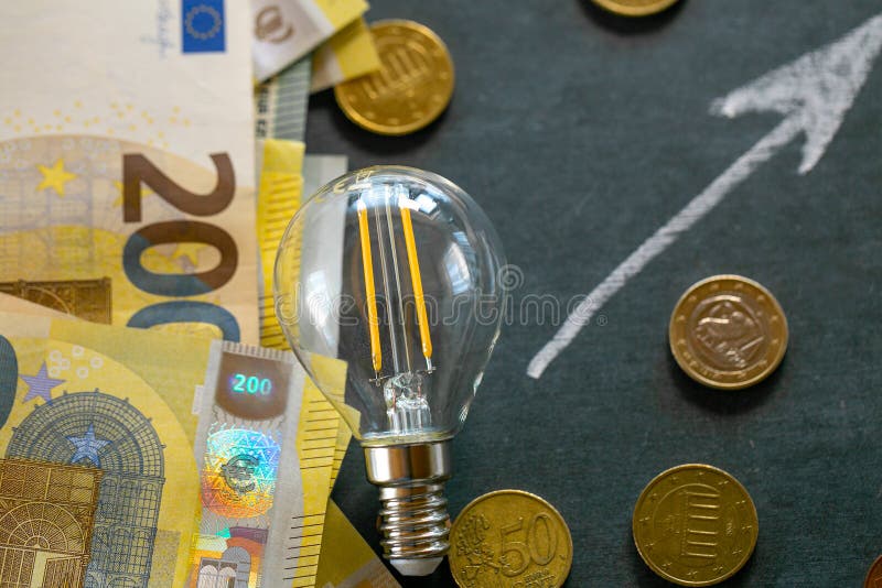 Rising electricity prices in Europe. Light bulb,euro bills and euro coins.Crisis of energy production in the EU