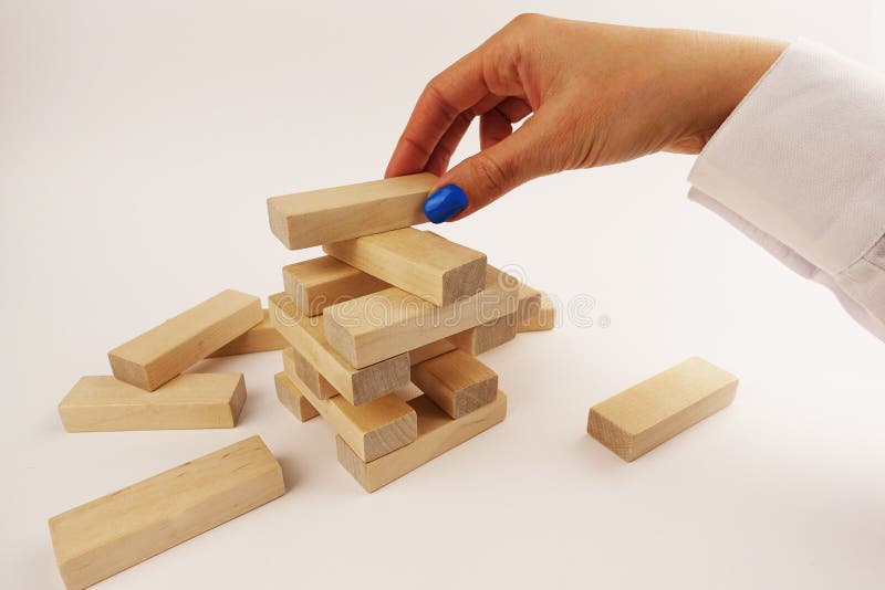 Risk assumption concept, business strategy with woman hand placing wooden pieces on a tower royalty free stock images Risk assumption concept, business strategy with woman hand placing wooden pieces on a tower royalty free stock images