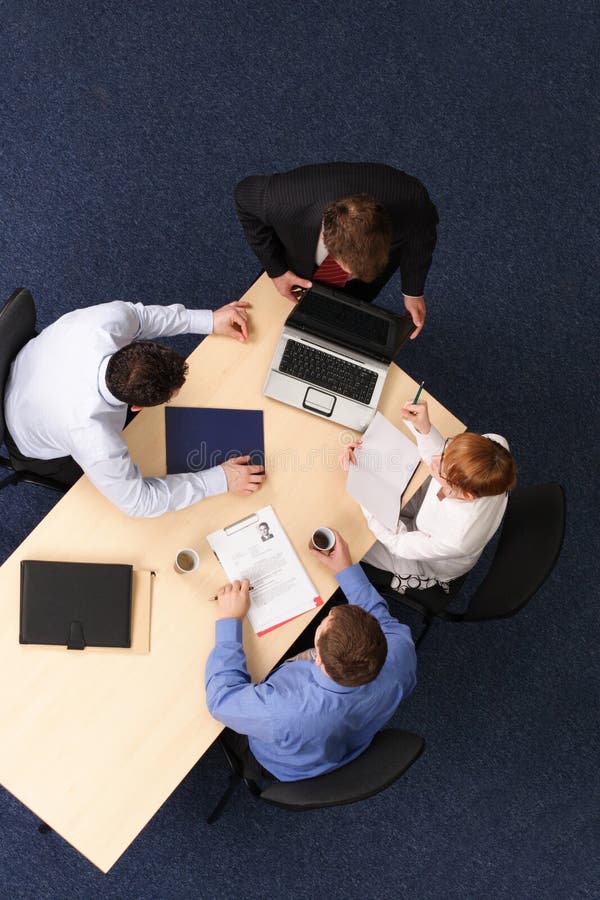 Businesspeople gathered around a table for a meeting, brainstorming. Aerial shot taken from directly above the table. Businesspeople gathered around a table for a meeting, brainstorming. Aerial shot taken from directly above the table.