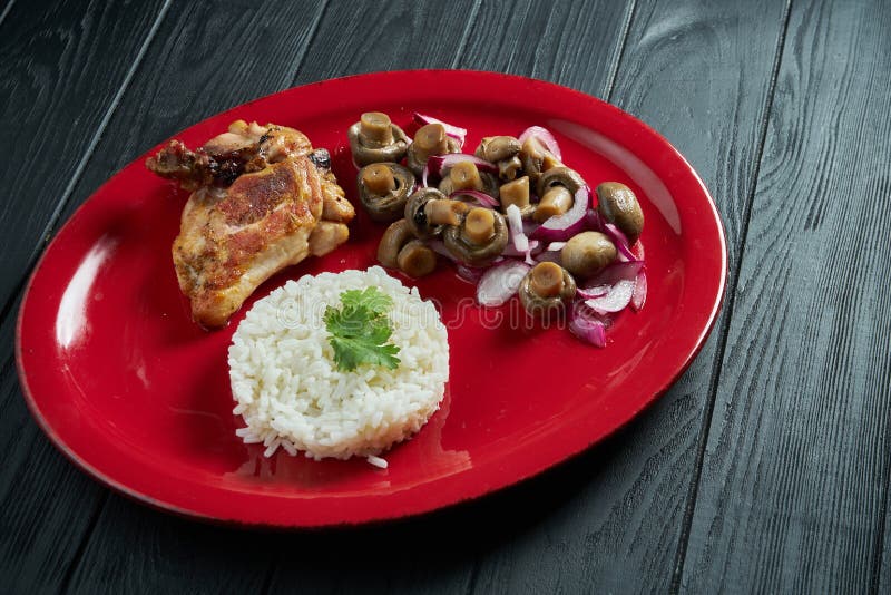 Riso bollito con funghi sottaceto e pollo su un piatto rosso su uno sfondo di legno nero Alimenti sani per la dieta fotografie stock libere da diritti Riso bollito con funghi sottaceto e pollo su un piatto rosso su uno sfondo di legno nero Alimenti sani per la dieta fotografie stock libere da diritti