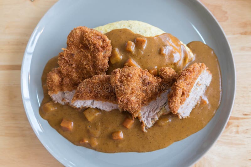 Riso dell'omelette con curry giapponese e Fried Pork Cutlet profondo impanato sulla Tabella di legno moderna fotografia stock Riso dell'omelette con curry giapponese e Fried Pork Cutlet profondo impanato sulla Tabella di legno moderna fotografia stock