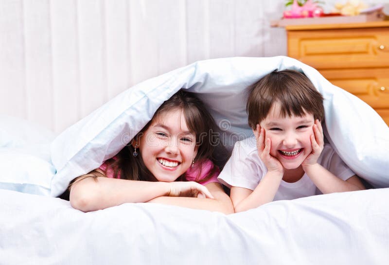 Brother and sister under blanket, laughing. Brother and sister under blanket, laughing