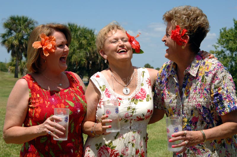 Senior friends outdoors holding drinks laughing during a picnic, party or vacation. Senior friends outdoors holding drinks laughing during a picnic, party or vacation
