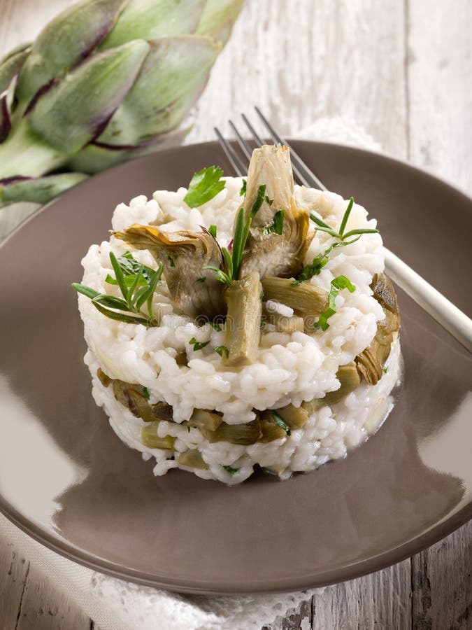 Risotto with artichokes over dish on wood background