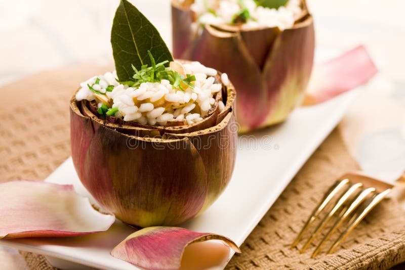 Stuffed artichokes with risotto on elegant table with golden fork. Stuffed artichokes with risotto on elegant table with golden fork