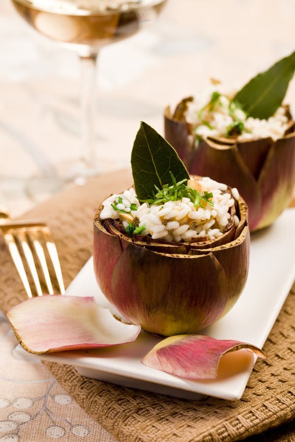 Stuffed artichokes with risotto on elegant table with golden fork. Stuffed artichokes with risotto on elegant table with golden fork