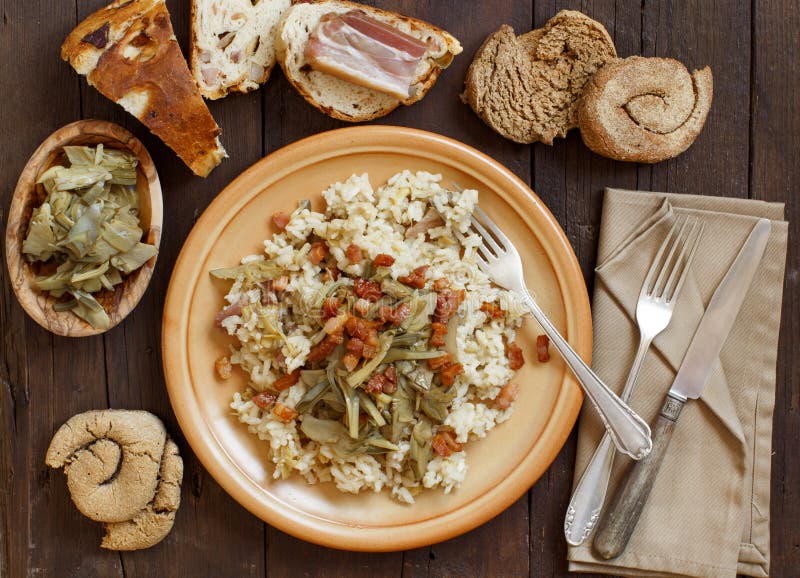 Risotto with artichokes and bacon top view on a wooden table