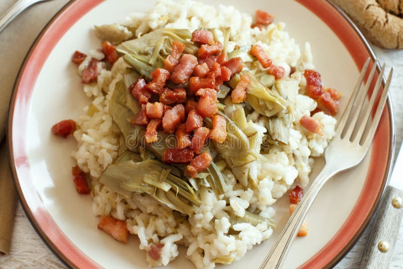 Risotto with artichokes and bacon top view on a wooden table