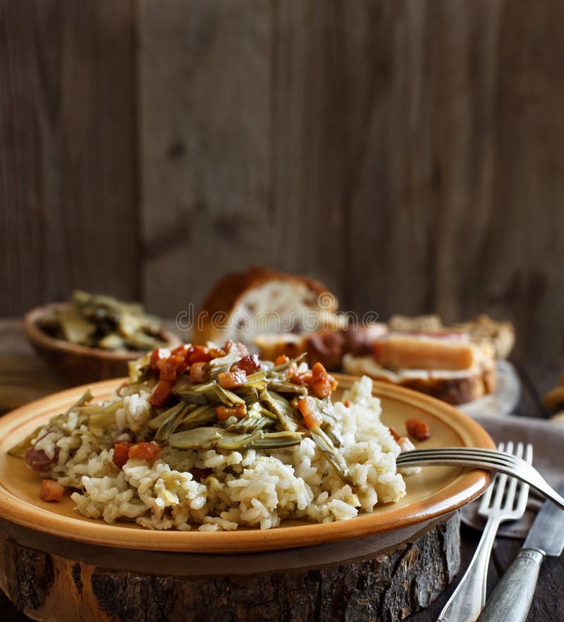 Risotto with artichokes and bacon top view on a wooden table