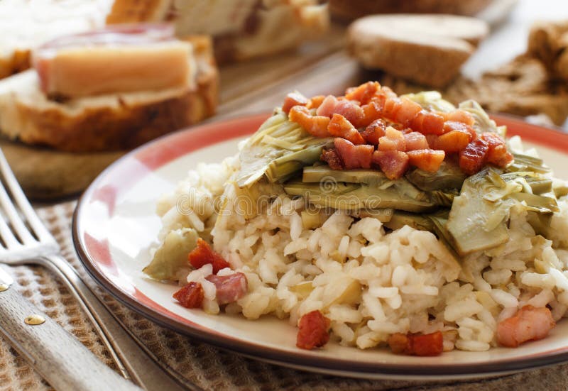 Risotto with artichokes and bacon top view on a wooden table