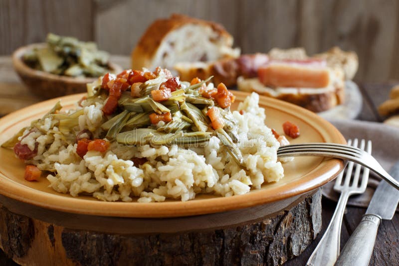 Risotto with artichokes and bacon top view on a wooden table