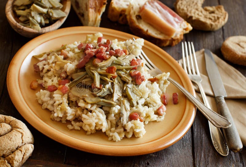 Risotto with artichokes and bacon top view on a wooden table