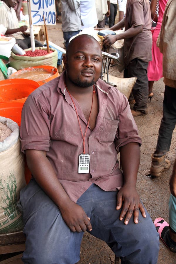 KAMPALA, UGANDA - SEPTEMBER 28, 2012. A market vendor poses for a picture next to his merchandise in the main market of Kampala, Uganda on September 28,2012. KAMPALA, UGANDA - SEPTEMBER 28, 2012. A market vendor poses for a picture next to his merchandise in the main market of Kampala, Uganda on September 28,2012.