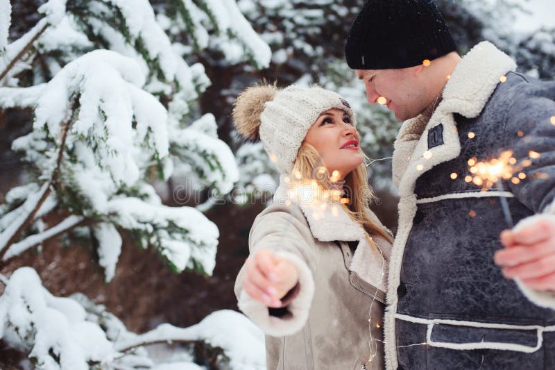 Ritratto all'aperto delle coppie romantiche felici che celebrano il Natale con i fuochi d'artificio brucianti fotografie stock Ritratto all'aperto delle coppie romantiche felici che celebrano il Natale con i fuochi d'artificio brucianti fotografie stock