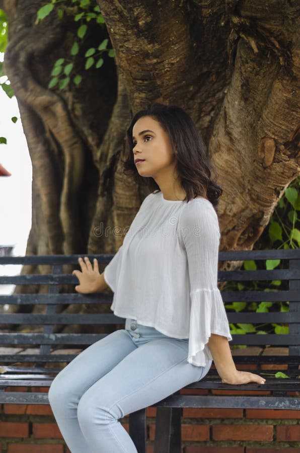 Ritratto all'aperto di giovani bei anni delle ragazze 9 - 25 che posano in via blusa bianca d'uso e jeans e sapatillas stretti immagine stock Ritratto all'aperto di giovani bei anni delle ragazze 9 - 25 che posano in via blusa bianca d'uso e jeans e sapatillas stretti immagine stock