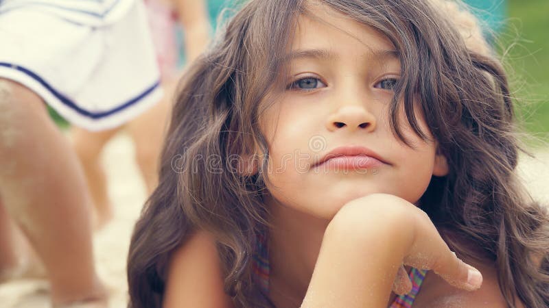 Ritratto all'aperto di piccola ragazza sveglia che si siede sulla sabbia della spiaggia Giorno pieno di sole di estate Feste feli fotografia stock libera da diritti Ritratto all'aperto di piccola ragazza sveglia che si siede sulla sabbia della spiaggia Giorno pieno di sole di estate Feste feli fotografia stock libera da diritti