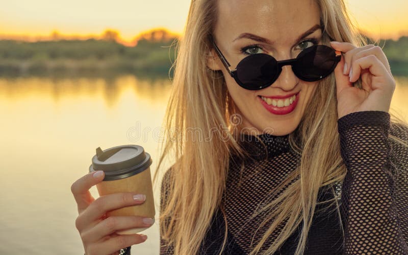 Ritratto all'aperto di una bella ragazza caucasica bionda felice con caffè a takeaway Giovane donna con i capelli lunghi con gli fotografie stock libere da diritti Ritratto all'aperto di una bella ragazza caucasica bionda felice con caffè a takeaway Giovane donna con i capelli lunghi con gli fotografie stock libere da diritti