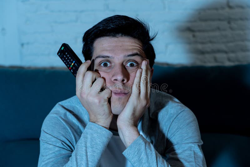 Ritratto alto vicino del giovane insonne annoiato sullo strato che guarda TV e che beve birra alla notte fotografie stock libere da diritti Ritratto alto vicino del giovane insonne annoiato sullo strato che guarda TV e che beve birra alla notte fotografie stock libere da diritti