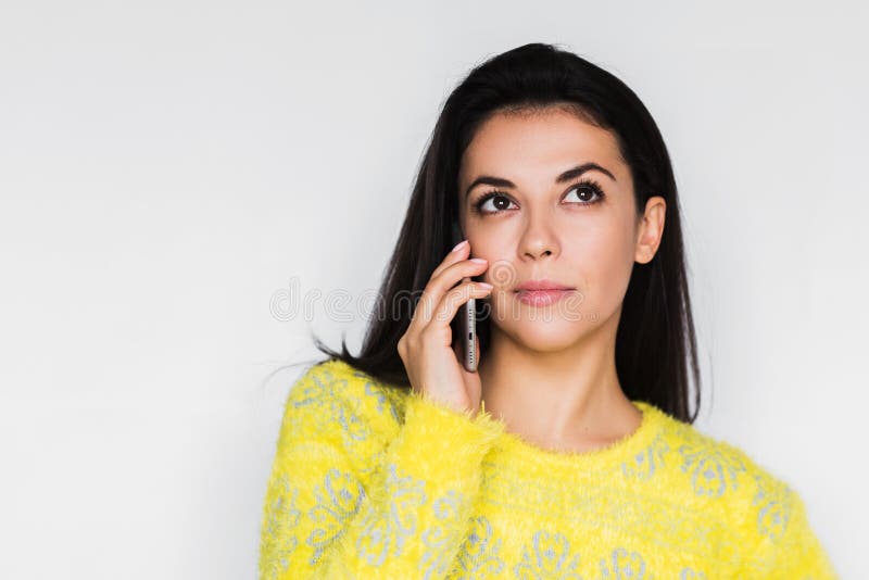Ritratto alto vicino di giovane bella donna seria che per mezzo dello Smart Phone sopra fondo grigio chiaro immagine stock libera da diritti Ritratto alto vicino di giovane bella donna seria che per mezzo dello Smart Phone sopra fondo grigio chiaro immagine stock libera da diritti