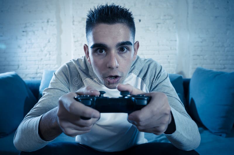 Ritratto alto vicino di giovane uomo dipendente che gioca video gioco alla notte nel concetto di dipendenza e di gioco