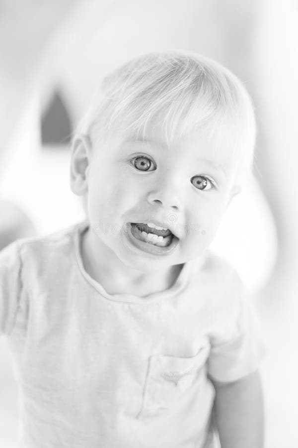 Ritratto bianco e nero di un bambino piccolo e carino che gioca all'aperto. giochi di bambini a scuola o fotografia stock