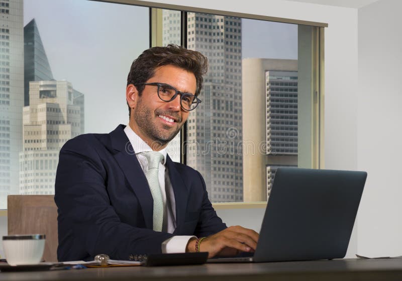 Ritratto corporativo di giovane uomo d'affari bello ed attraente felice che lavora allo scrittorio del computer in ufficio modern fotografie stock libere da diritti Ritratto corporativo di giovane uomo d'affari bello ed attraente felice che lavora allo scrittorio del computer in ufficio modern fotografie stock libere da diritti