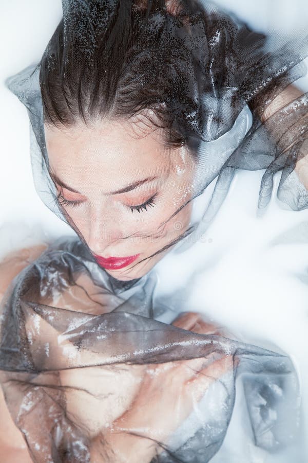 Ritratto creativo della bella donna sensuale con Tulle nera nel bagno del latte immagini stock Ritratto creativo della bella donna sensuale con Tulle nera nel bagno del latte immagini stock