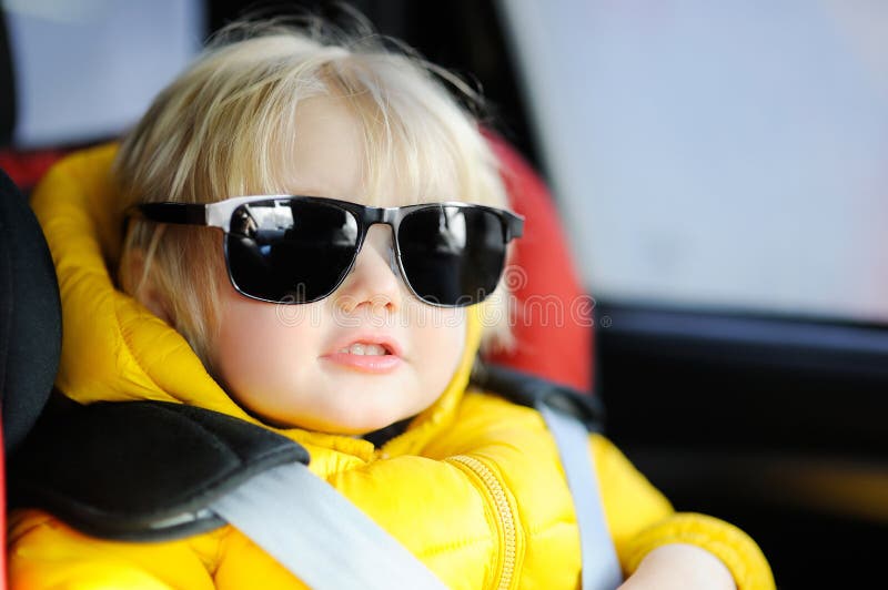 Ritratto degli occhiali da sole d'uso del ` s del padre del ragazzino divertente sveglio che si siedono nella sede di automobile fotografia stock Ritratto degli occhiali da sole d'uso del ` s del padre del ragazzino divertente sveglio che si siedono nella sede di automobile fotografia stock