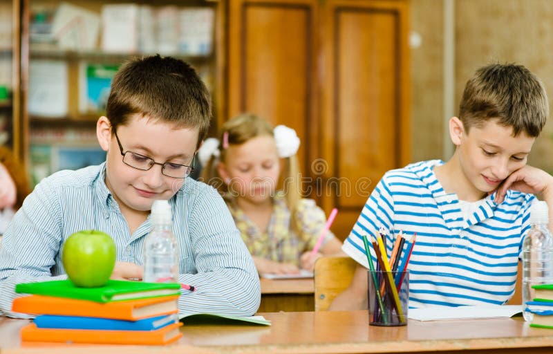Ritratto degli studenti che scrivono l'esame nella classe fotografia stock Ritratto degli studenti che scrivono l'esame nella classe fotografia stock