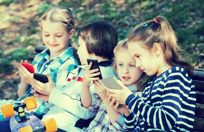 Ritratto dei bambini positivi che giocano con i telefoni fotografia stock Ritratto dei bambini positivi che giocano con i telefoni fotografia stock