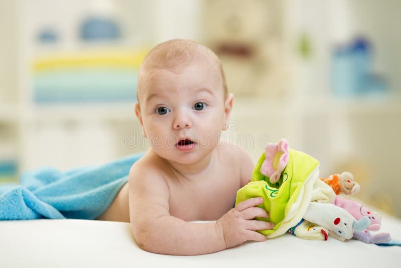 Ritratto del bambino sorridente sveglio che si trova sul letto dopo che ha bathtime immagini stock Ritratto del bambino sorridente sveglio che si trova sul letto dopo che ha bathtime immagini stock