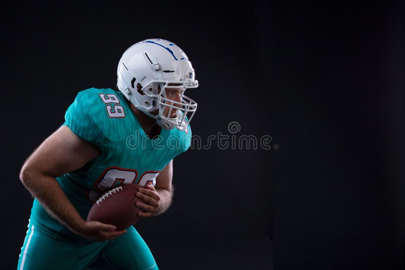 Ritratto del giocatore di football americano che tiene una palla in entrambi il suo armi Copi lo spazio rugby fotografie stock Ritratto del giocatore di football americano che tiene una palla in entrambi il suo armi Copi lo spazio rugby fotografie stock