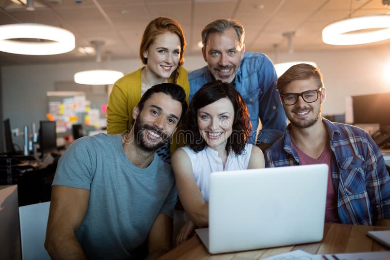 Ritratto del gruppo creativo felice di affari che lavora al computer portatile fotografia stock libera da diritti Ritratto del gruppo creativo felice di affari che lavora al computer portatile fotografia stock libera da diritti