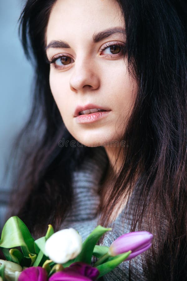 Ritratto del primo piano di giovane bella donna castana con i tulipani immagini stock libere da diritti Ritratto del primo piano di giovane bella donna castana con i tulipani immagini stock libere da diritti