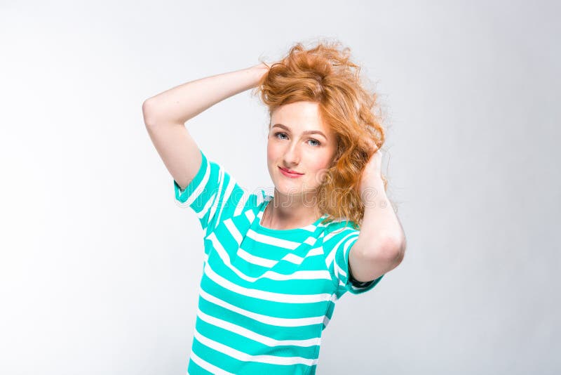 Ritratto del primo piano di giovane, bella donna con capelli ricci rossi in un vestito da estate con le strisce del blu nello stu fotografia stock Ritratto del primo piano di giovane, bella donna con capelli ricci rossi in un vestito da estate con le strisce del blu nello stu fotografia stock