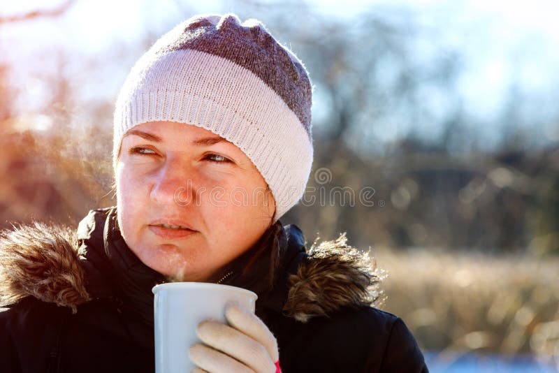 Ritratto del tè bevente della giovane donna all'aperto alla via di inverno fotografia stock Ritratto del tè bevente della giovane donna all'aperto alla via di inverno fotografia stock