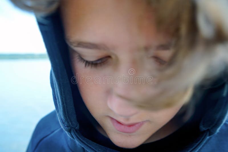 Ritratto dell'adolescente triste sulla banca del fiume o del lago Ragazzo sveglio con capelli ricci in un cappuccio che dura nell fotografie stock Ritratto dell'adolescente triste sulla banca del fiume o del lago Ragazzo sveglio con capelli ricci in un cappuccio che dura nell fotografie stock