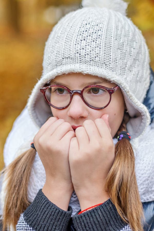 Ritratto dell'adolescente in vetri, soffiante sulle sue mani per tenere caldo nel freddo immagini stock libere da diritti Ritratto dell'adolescente in vetri, soffiante sulle sue mani per tenere caldo nel freddo immagini stock libere da diritti
