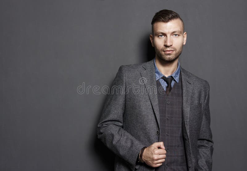 Ritratto dell'uomo bello sicuro alla moda in vestito sul fondo grigio della parete Dell'uomo d'affari di sguardi sguardo seriamen fotografia stock libera da diritti Ritratto dell'uomo bello sicuro alla moda in vestito sul fondo grigio della parete Dell'uomo d'affari di sguardi sguardo seriamen fotografia stock libera da diritti